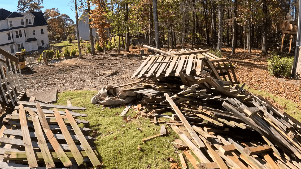 Before: Pile of wooden fence panels and debris in backyard